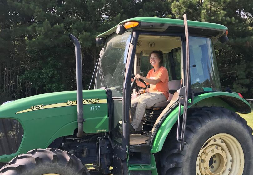 A Carbon Robotics team member poses for a photo inside a tractor.&nbsp;