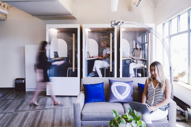 Mirakl team members in individual working “booths” in their office, with nearby lounge seating area.&nbsp;