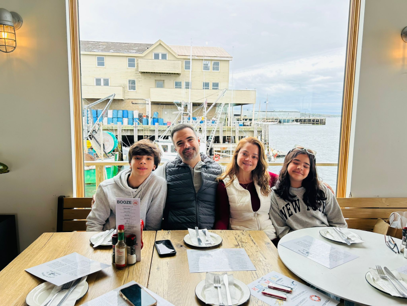 Felipe Dias Morais Magalhães, his wife and their two children pose for a photo at a restaurant in New England.&nbsp;