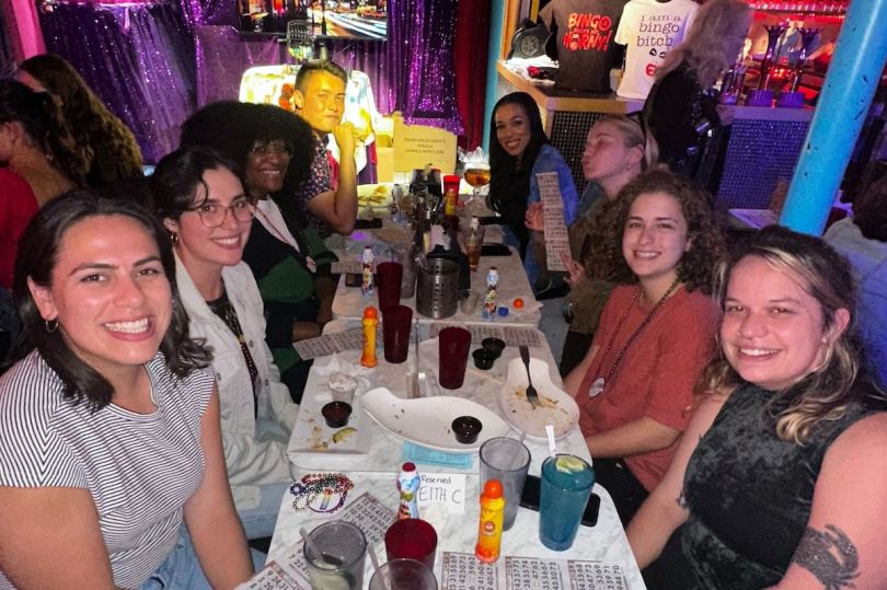 Nowsta team members seated around a table at a company happy hour.&nbsp;