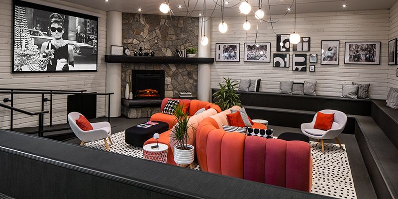 A collaborative seating space with a fireplace that is divided by 2 couches to accommodate two groups.