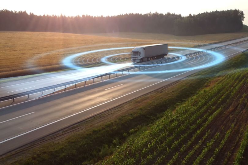 A semi-truck on a highway with digital wave patterns around it.