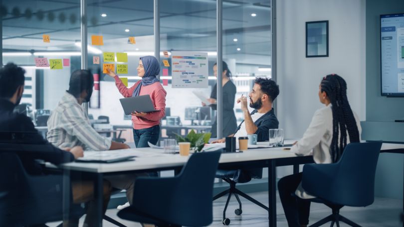 A team of employees looks at a speaker during a planning session in a conference room.  