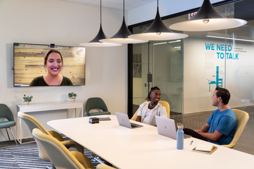 two sprout social team members sitting at a conference table meeting a colleague remotely