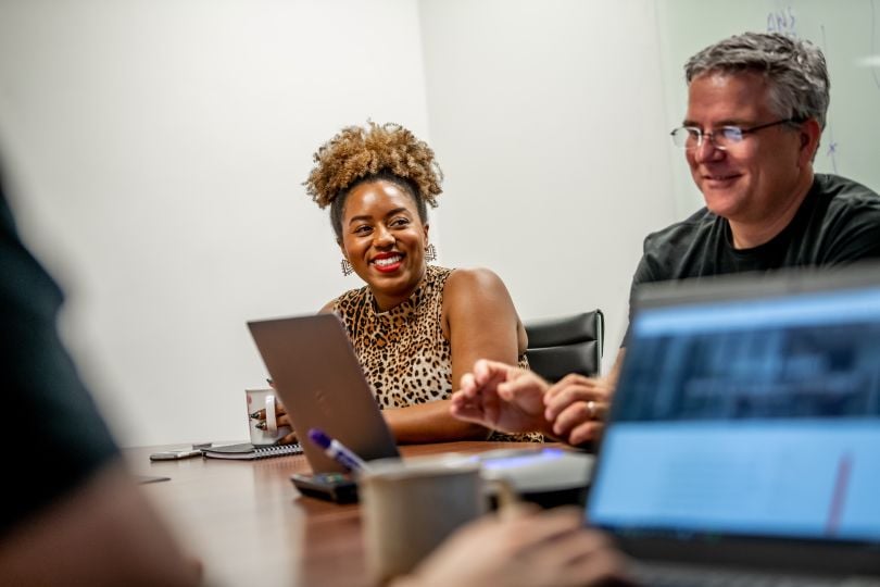 Tango Card employees talk and smile in a conference room.