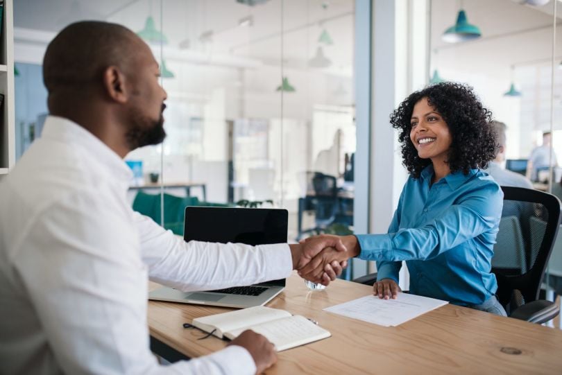 A manager shakes hands with an employee.