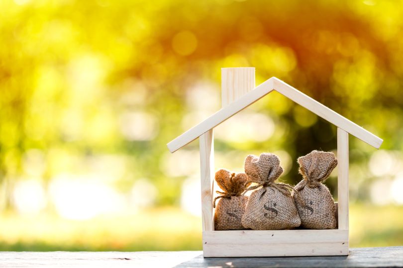A small house full of money bags is pictured.