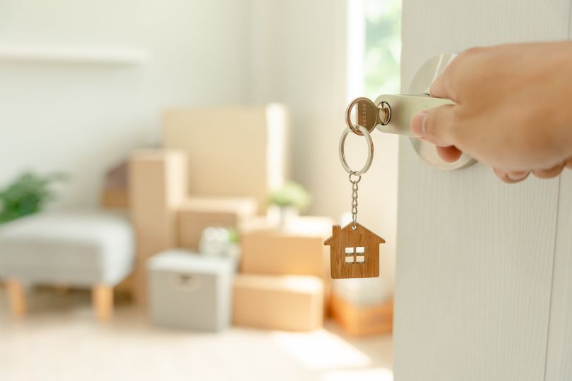 A person is pictured opening the door to a new home.