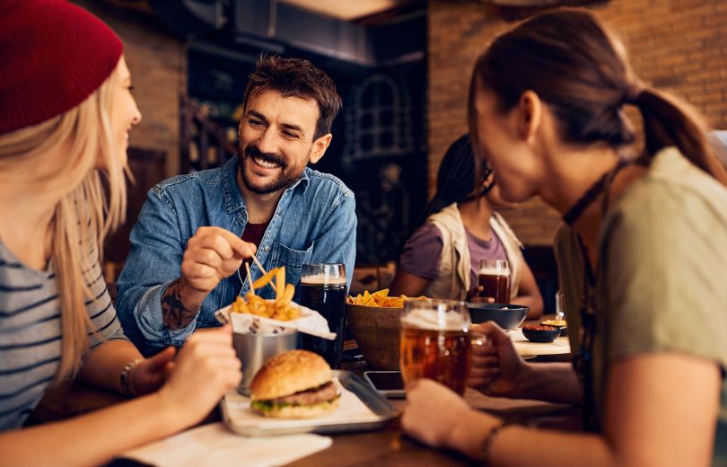 People smiling and eating french fries with toothpicks.&nbsp;