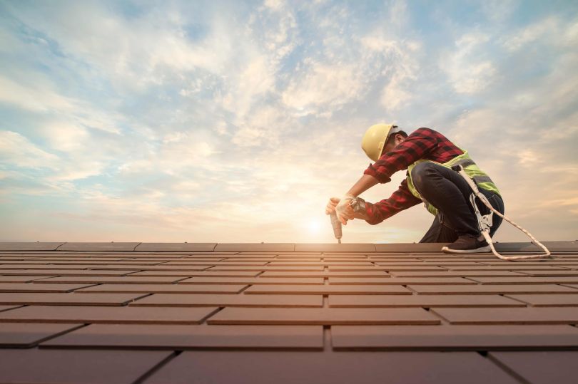 A contractor works to repair a shingled roof.