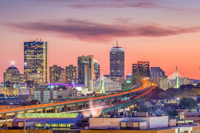 The Boston skyline with bridges and highways at dusk.