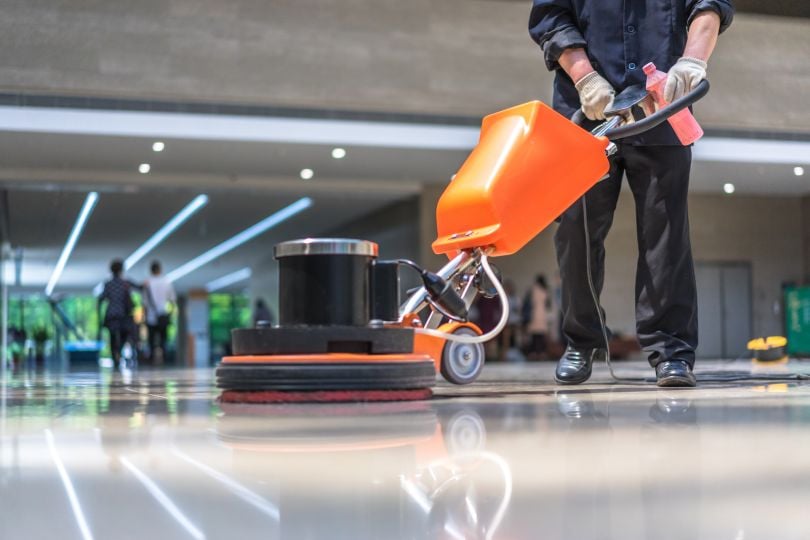 A person cleans a floor with a machine.