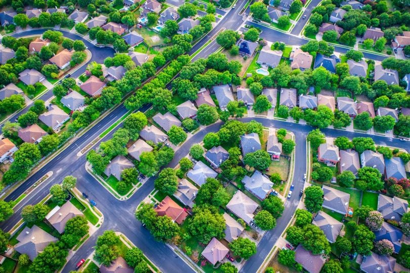 An overhead shot of a neighborhood of single-family homes surrounded by trees