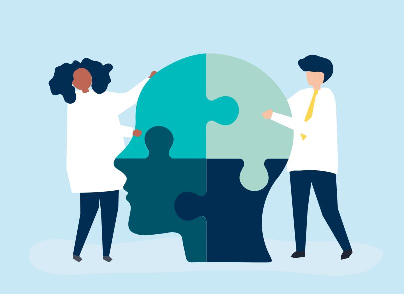 Mental health professionals hold puzzle pieces that form a human head. 