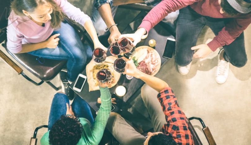 Overhead view of coworkers raising glasses together to toast at a happy hour event.