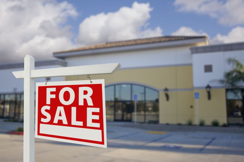 A business with a "for sale" sign. 