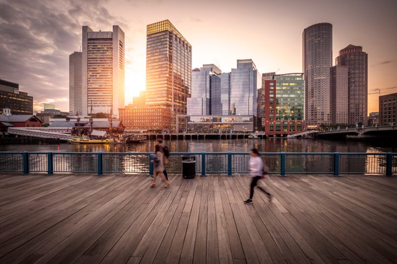 Downtown Boston at sunset with people walking in the foreground.