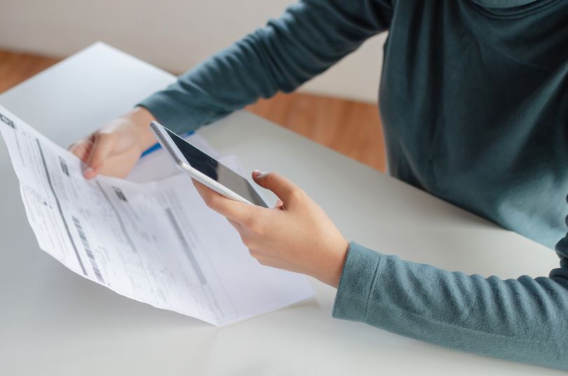 A person uses their phone to pay a bill online.