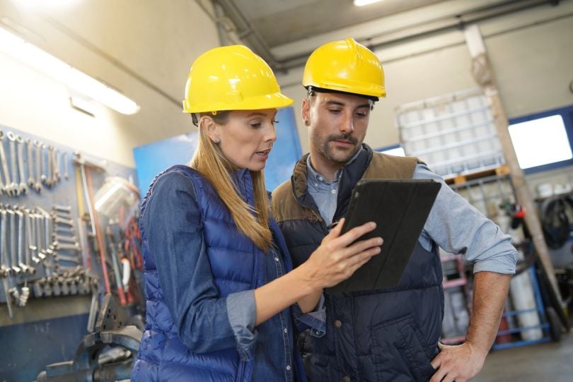 A manager provides instructions to employees using an electronic tablet.
