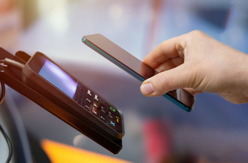 Someone holds a phone over a payment system.