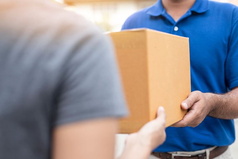 A delivery person hands someone a box.