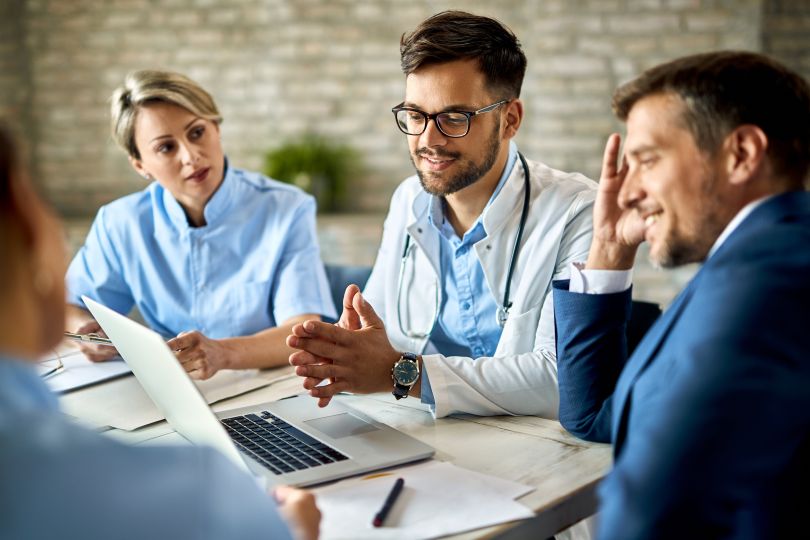 Group of healthcare professionals meeting with laptop open