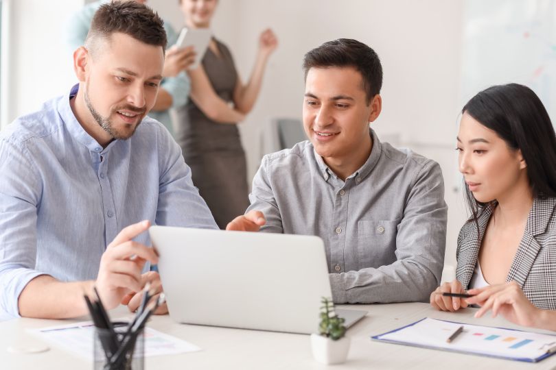 A group of professionals work around a laptop. 