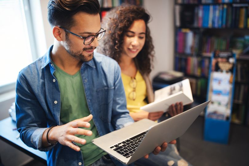 Two coworkers looking at a laptop