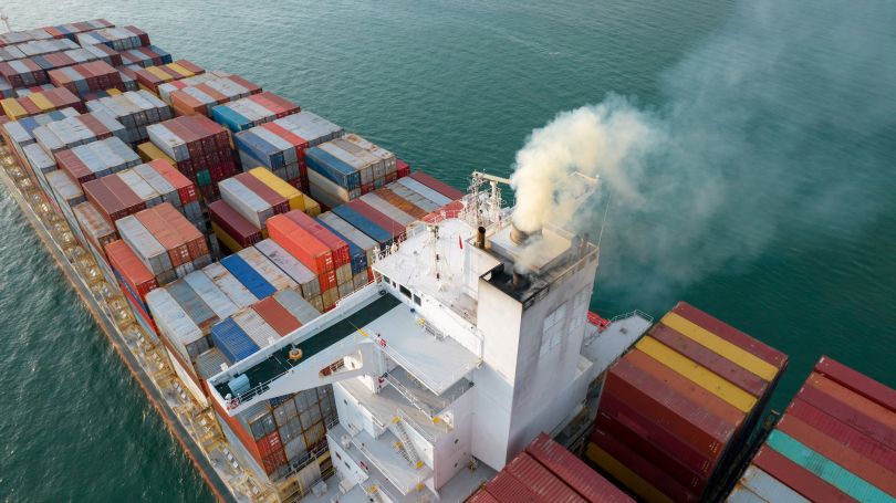 A freight ship sails with several cargo containers onboard.