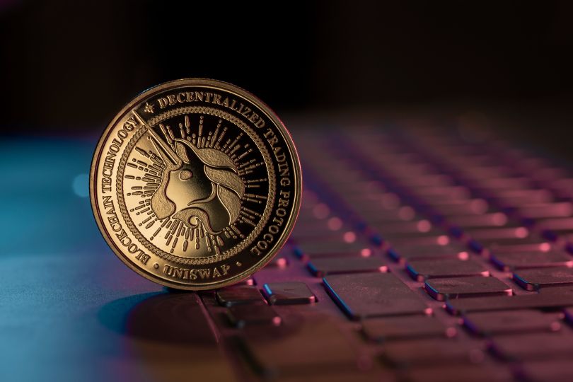 A physical Uniswap coin is displayed on a keyboard.