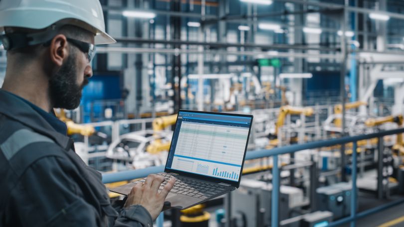 A technician works with robots on a factory floor