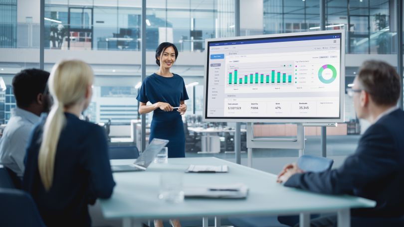 stock photo of person giving a presentation in front of three people in a meeting room