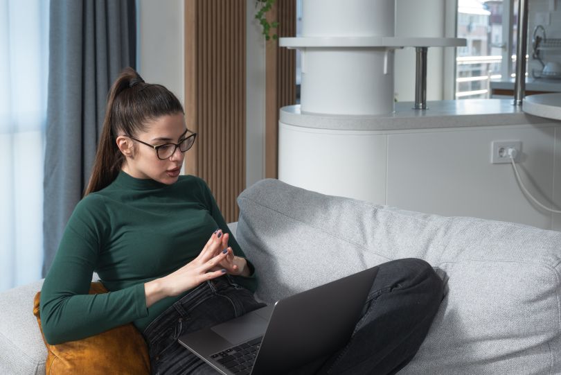 A young woman engages in a therapy session via her laptop
