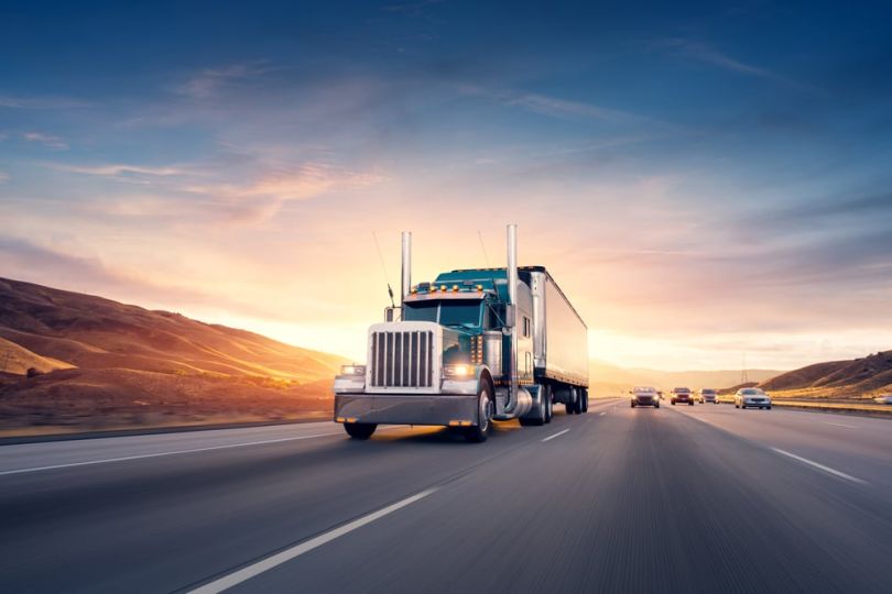 A semi-truck on a freeway pulling load.