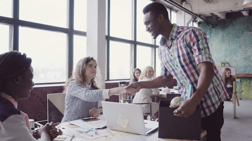 New hire shaking hands with coworkers