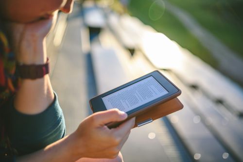 A woman reads an e-reader. 