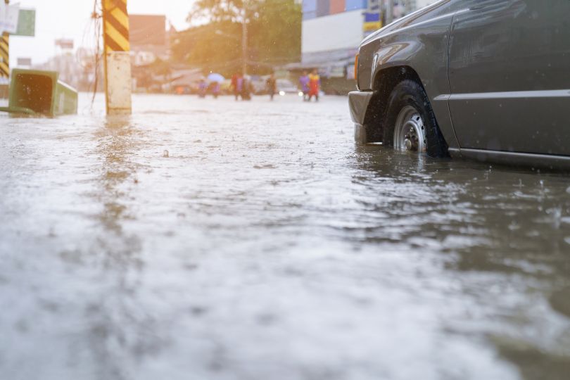 A car drives through a flooded street.