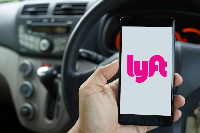 Person in a car holding a phone with Lyft on the phone