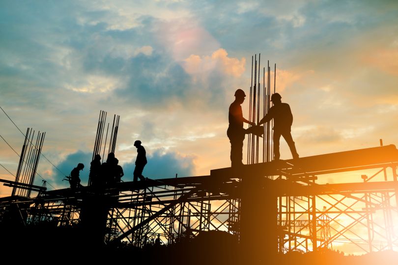 Construction workers are pictured on scaffolding.