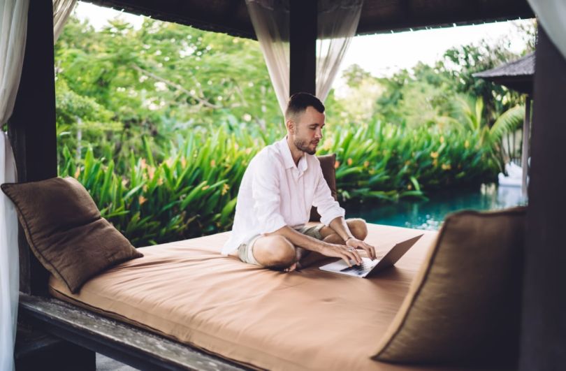 A man working on a laptop in a tranquil outdoor setting.