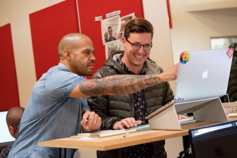 two men looking at a laptop