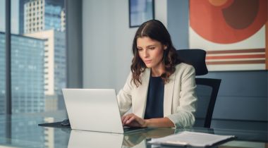 Woman typing on laptop while sitting at desk.